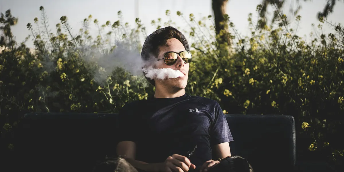 man sitting on a bench and vaping relaxed