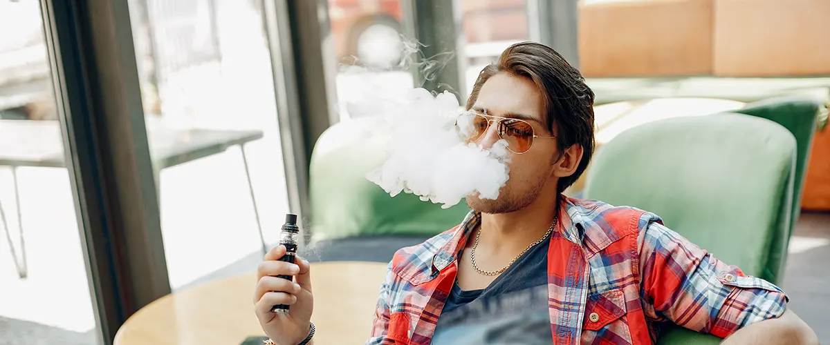 stylish elegant man sitting cafe with his vaping