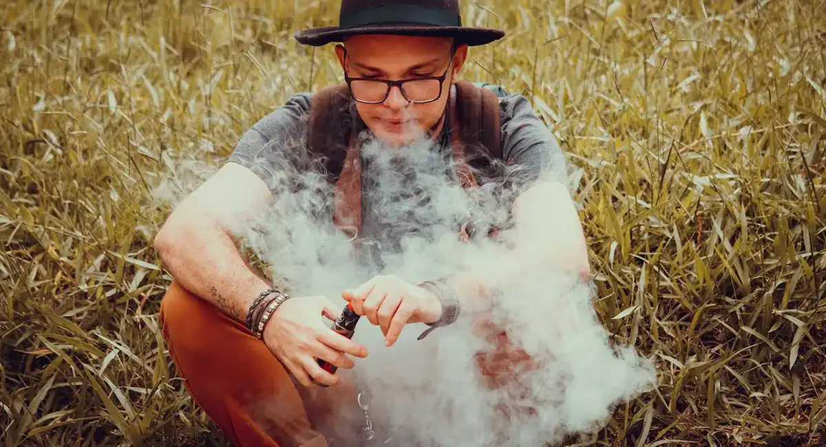 a man sitting in the field and vaping provided by the vape coil
