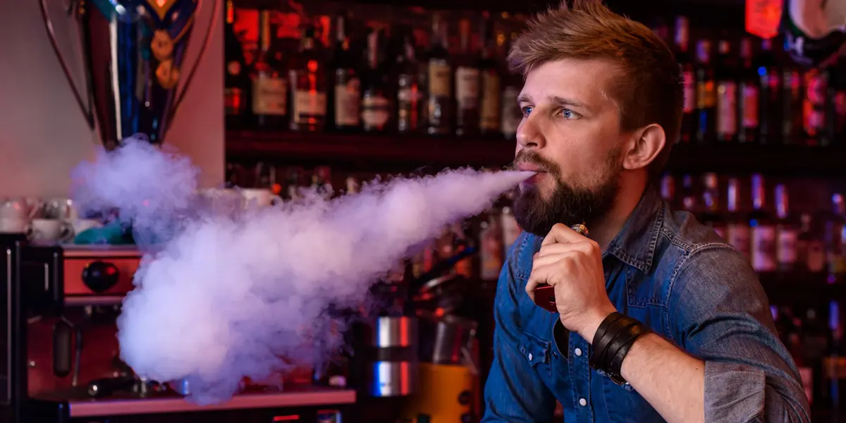 man is taking disposable vape in a vape shop