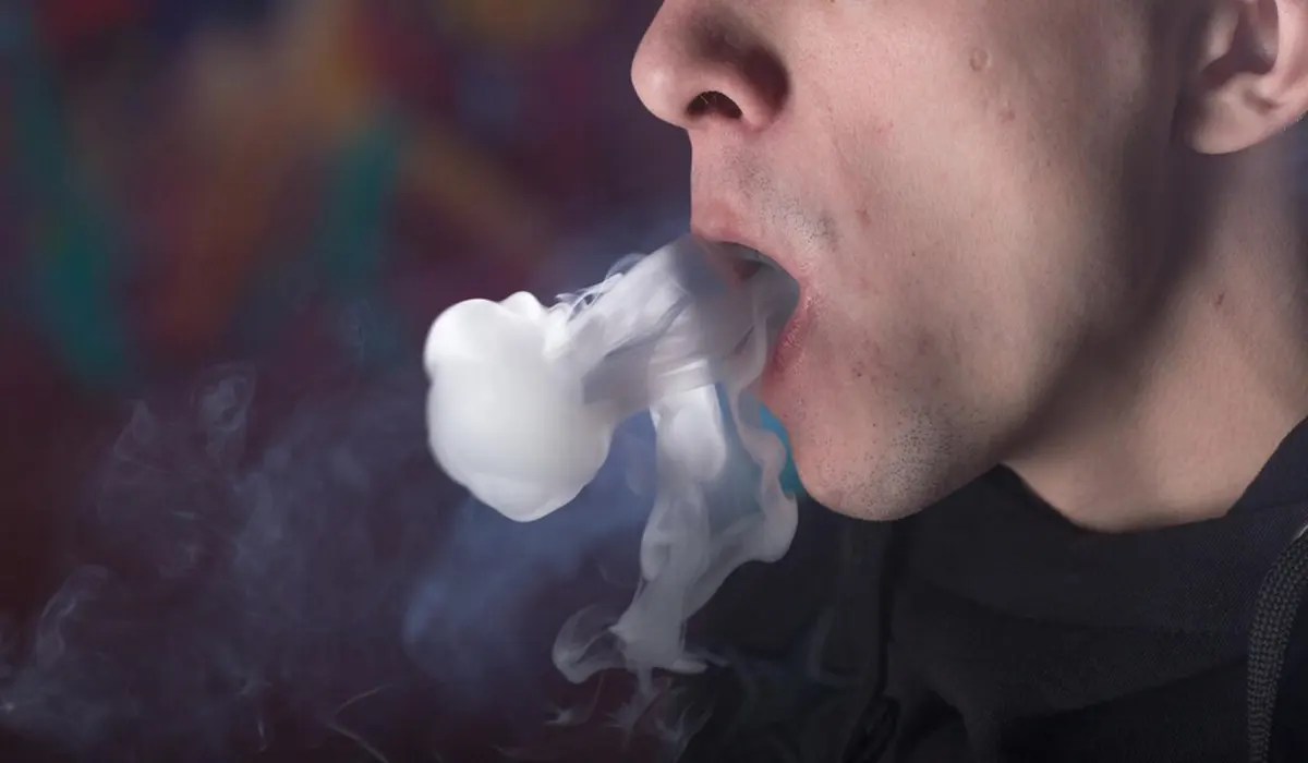man smoking his disposable vape and exhaling cool vapor